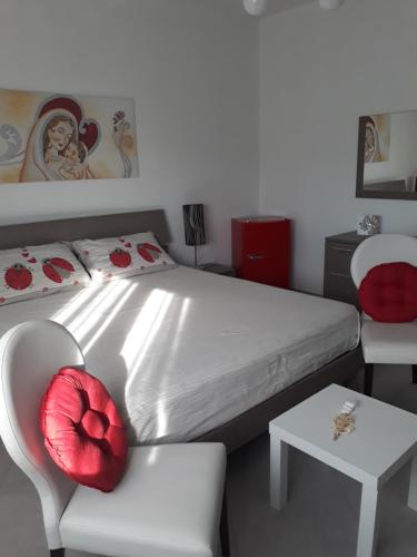 una camera da letto con un letto con un cuscino rosso su una sedia di Belvedere a Policoro