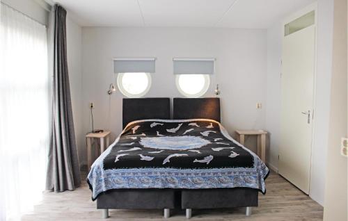a bedroom with a black bed with two windows at Nice Home In Workum With 3 Bedrooms And Wifi in Workum