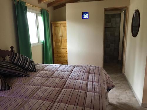 1 dormitorio con cama, ventana y puerta en Mono Ambiente Clarien en Lago Puelo