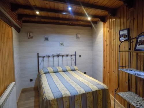 1 dormitorio con 1 cama en una habitación con paredes de madera en Casa Rural Generoso, en Madroñal