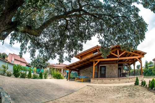 a house with a large tree in front of it at El Encinar in Maello
