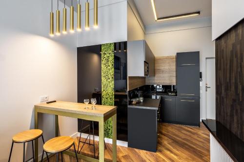 a kitchen with a table and stools in a room at Apartamenty Nowa Kamienica Częstochowa Centrum Szymanowskiego 22A in Częstochowa
