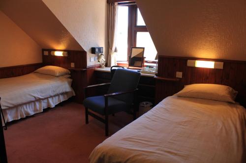 a hotel room with two beds and a desk and a chair at Beeches Aberdeen in Aberdeen