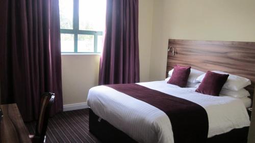 a hotel room with a large bed with purple curtains at Mourne Country Hotel in Newry