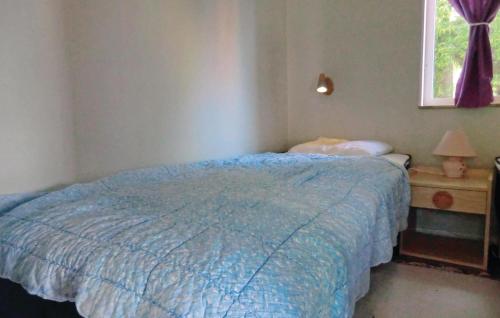 a bedroom with a blue bed and a window at Lovely Home In Frjestaden With Ethernet Internet in Färjestaden