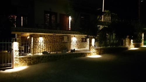a building with lights on a fence at night at Stone house with seaview in Nea Potidaea