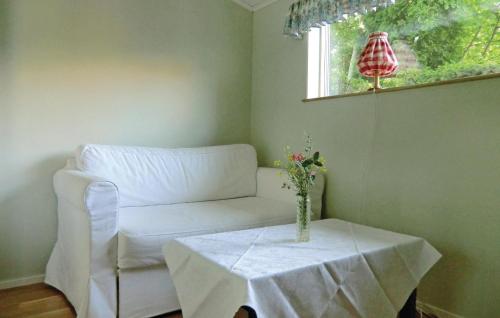 einen weißen Stuhl und einen Tisch mit einer Vase drauf in der Unterkunft Lovely Home In Frjestaden With Ethernet Internet in Färjestaden