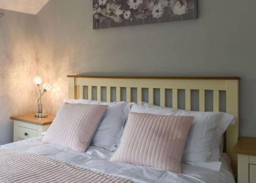 a bedroom with a bed with two pink pillows at Hollyhock Cottage in Ashford