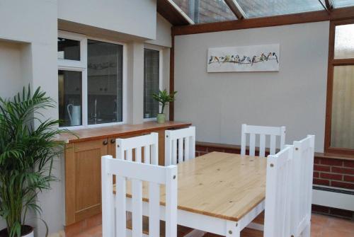 a dining room with a wooden table and chairs at Hollyhock Cottage in Ashford