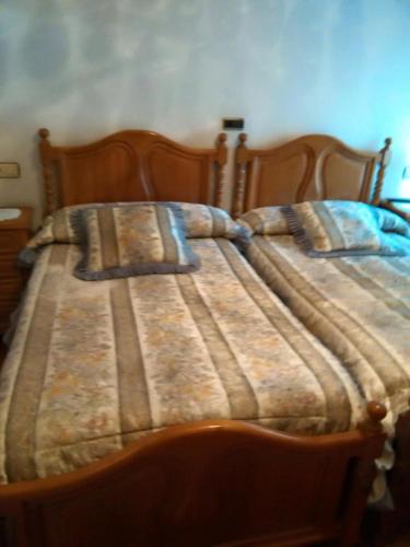 a bed with a striped blanket on top of it at Hostal La Parra in Vegadeo