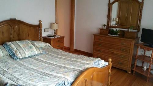 ein Schlafzimmer mit einem großen Bett mit einer Kommode und einem Spiegel in der Unterkunft Hostal La Parra in Vegadeo