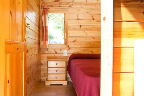 a small bedroom with a bed in a wooden cabin at Bungalows Verneda Mountain Resort in Arrós
