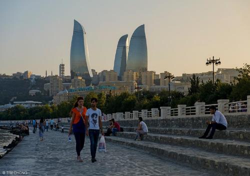 Un uomo e una donna che camminano per strada con una città sullo sfondo di Квартира в Ичери шехер a Baku