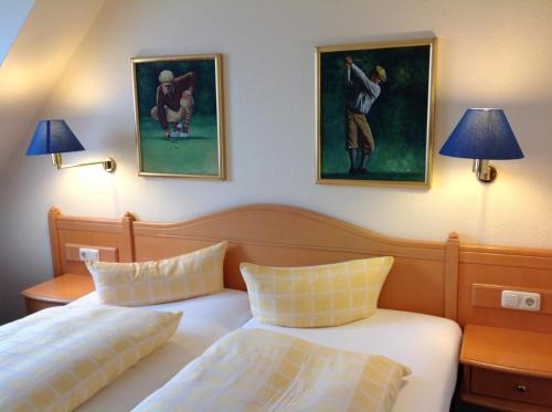 a bedroom with two beds and two paintings on the wall at Dünenhotel am Meer in Warnemünde