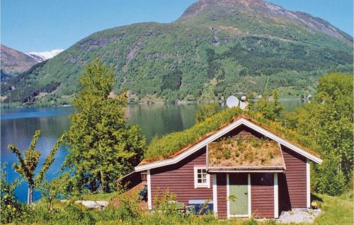 an old house on the side of a lake with a mountain at Beautiful Home In Skei I Jølster in Årdal