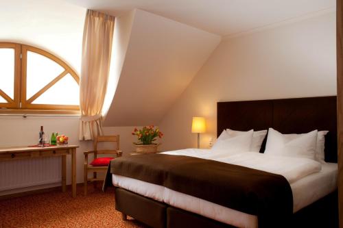 a bedroom with a bed and a desk and a window at Hotel Zamek Bobolice in Bobolice