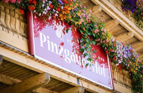 a sign on the side of a building with flowers at Pension Pinzgauer Hof in Maria Alm am Steinernen Meer