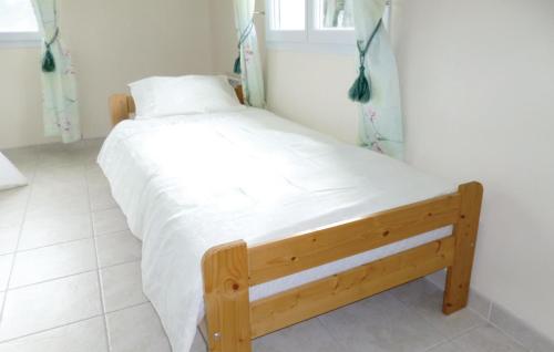 Schlafzimmer mit einem Holzbett mit weißer Bettwäsche in der Unterkunft 1 Bedroom Gorgeous Home In La Chapelle En Juger in Montreuil-sur-Lozon