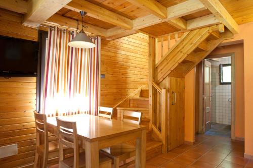 a dining room with a wooden table and chairs at Bungalows Verneda Mountain Resort in Arrós