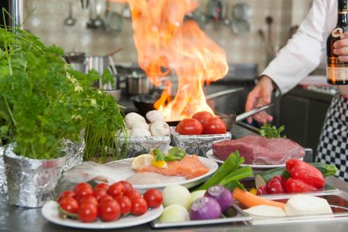 a chef preparing food in a kitchen with plates of food at Hotel Eisensteiner Hof in Bayerisch Eisenstein
