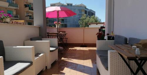 a patio with a table and a pink umbrella at B&B Purple Italy in Fiumicino