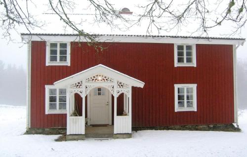 a red barn with a white door in the snow at Gorgeous Home In Vrigstad With Wifi in Vrigstad