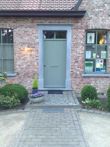 a brick house with a green door and flowers at B&B Zinnen en Minnen in Herselt