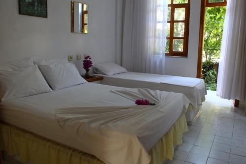 two beds in a room with white sheets and flowers at Rose Pension in Dalyan