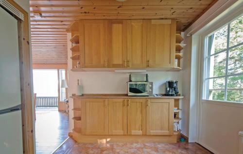 a kitchen with wooden cabinets and a microwave at Lovely Home In Kvicksund With Sauna in Kvicksund