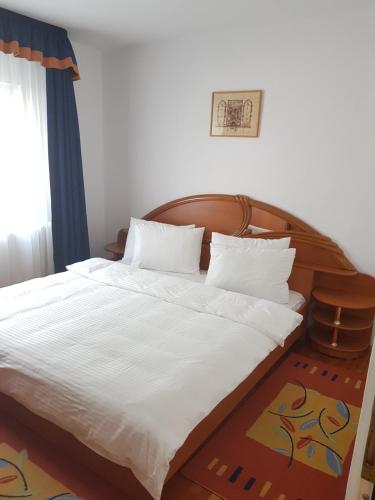 a bedroom with a large white bed with a wooden headboard at Apartament Melinda in Oradea