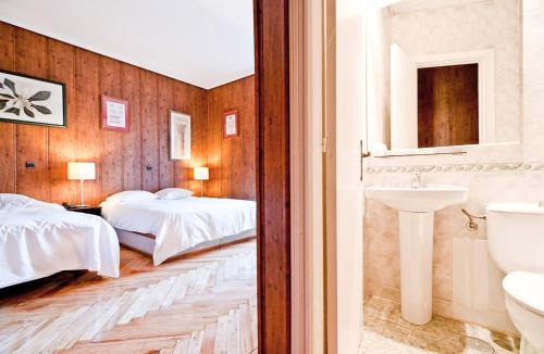 Una habitación de hotel con dos camas y un lavabo. en Hostal Asunción, en Madrid