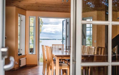 a dining room with a table and chairs with a view of the water at Lovely Home In Kvicksund With Sauna in Kvicksund