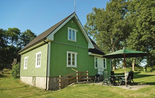 a green house with a table and an umbrella at Holiday Home Kallinge With A Fireplace 07 in Möljeryd