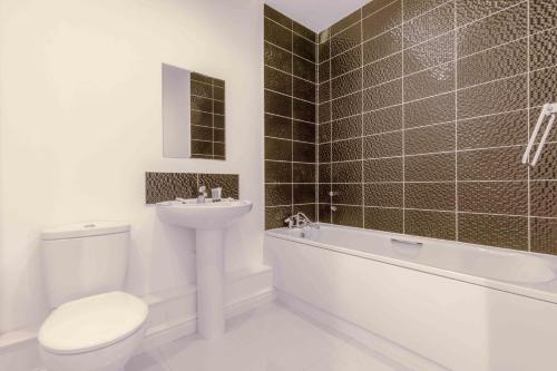 La salle de bains est pourvue de toilettes, d'un lavabo et d'une baignoire. dans l'établissement The Penthouse @ Waterside Grange, à Slough