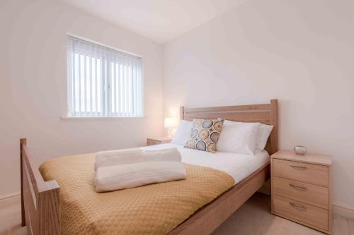 - une chambre avec un lit avec un cadre en bois et une fenêtre dans l'établissement The Penthouse @ Waterside Grange, à Slough
