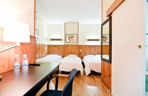 Una habitación de hospital con dos camas y un escritorio. en Hostal Asunción, en Madrid