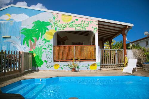 una casa con un mural junto a una piscina en Holiday Home Soleil de Gwada, en Sainte-Anne