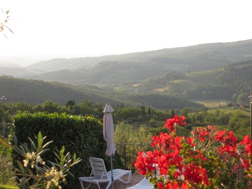 a patio with an umbrella and red flowers at Borgo Sicelle Residence in San Donato in Poggio