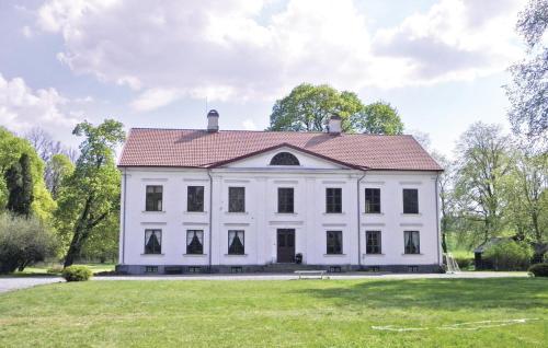 ein weißes Haus mit rotem Dach auf einem Grasfeld in der Unterkunft Holiday Home Flishult Gård Vetlanda in Vetlanda