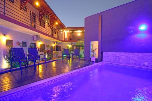 einen Pool in einem Haus mit lila Lichtern in der Unterkunft Pousada Recanto da Morada in Olímpia