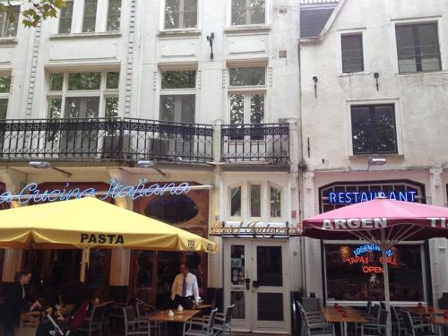a street with tables and umbrellas in front of buildings at Imperial Hotel Amsterdam in Amsterdam