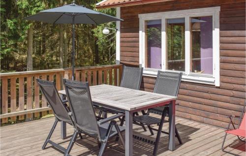 a wooden table with chairs and an umbrella on a deck at 3 Bedroom Nice Home In Hallaryd in Hallaryd