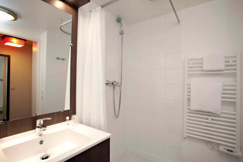 W łazience znajduje się umywalka i prysznic. w obiekcie Aparthotel Adagio Access Paris Asnières w mieście Asnières-sur-Seine