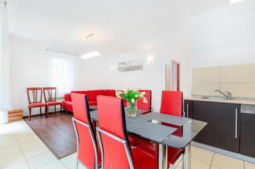een keuken en eetkamer met een tafel en rode stoelen bij Apartamenty Morskie Oko by Renters in Międzyzdroje