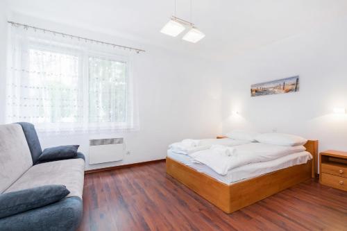 a white bedroom with a bed and a couch at Apartamenty Morskie Oko by Renters in Międzyzdroje