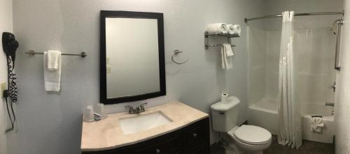 a bathroom with a sink and a toilet and a mirror at Budget Inn & Suites in Oklahoma City