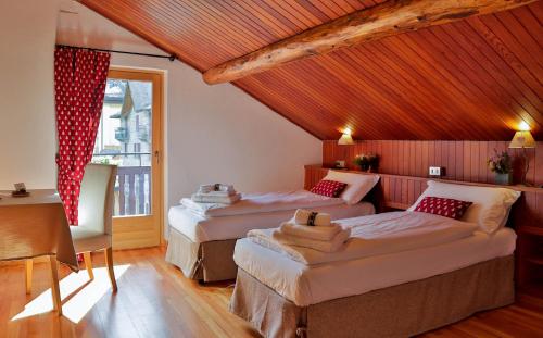 a bedroom with three beds and a table and a window at Hotel Roseg in Chiesa in Valmalenco