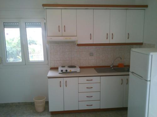 a kitchen with white cabinets and a white refrigerator at Kalaitzis Apartments in Kalivia Poligirou