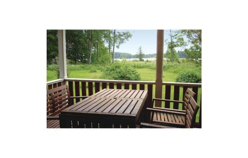 a wooden table and benches on a porch with a window at Cozy Home In Katrineholm With Lake View in Katrineholm
