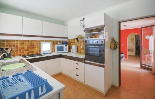 une cuisine avec des armoires blanches et un four à plaques de cuisson dans l'établissement Lovely Home In Bagnols En Foret, à Bagnols-en-Forêt